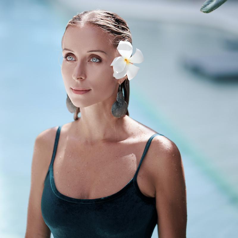 woman in black bathing suit with flower in her hair